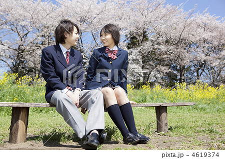 ベンチに座り話をする高校生カップルの写真素材