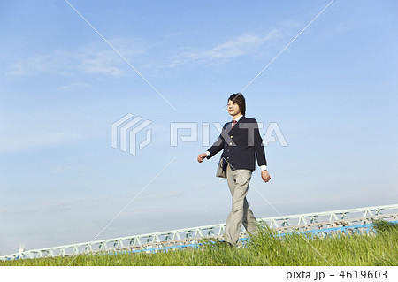 土手を歩く男子高校生の写真素材