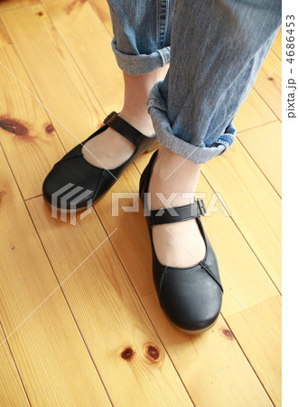 レザーのストラップシューズを履いている女性の足 4686453