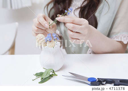 小さな花瓶に花を挿す女性の写真素材
