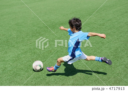 ユニフォームを着たサッカー少年のダイナミックなシュートシーンの写真素材
