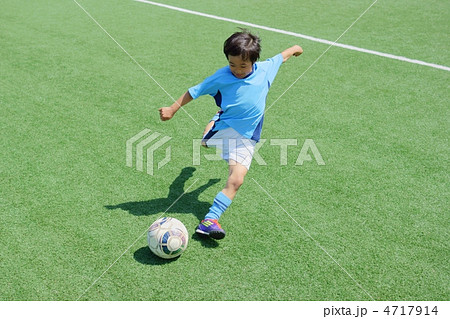 ユニフォームを着たサッカー少年のダイナミックなシュートシーンの写真素材
