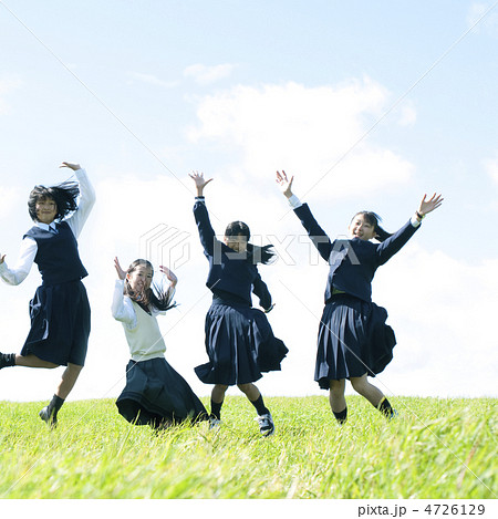 草原でジャンプをする中学生の写真素材