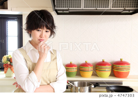 キッチンで悩んでいるエプロン姿の女性 キッチンで悩んでいるエプロン姿の女性 4747303