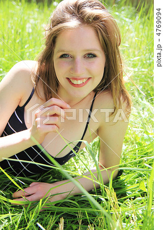 芝生に寝そべる笑顔の女性外国人の写真素材