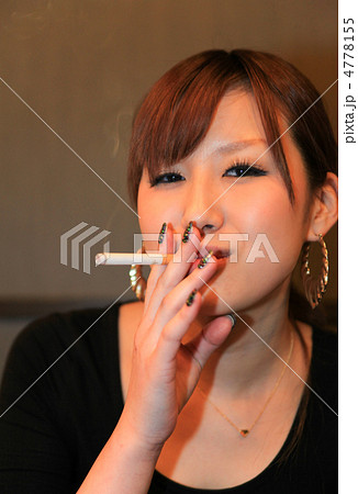タバコを吸う若くて粋な女性 美人 屋内 の写真素材