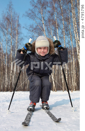 Young boy skates on cross-country skis inside winter forest at s 4795796