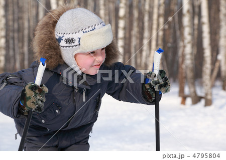Portrait of young boy with ski poles looking to side inside wint 4795804