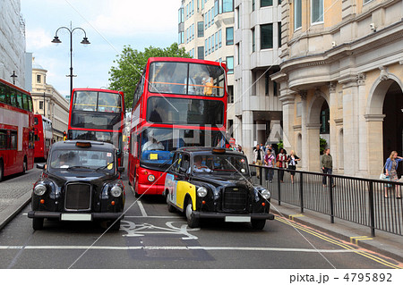 Red double-deckers with tourists and taxi on street of London, E 4795892