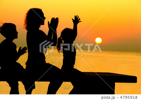 Mother with two children sits on  bench on  beach  on sunset and 4795918