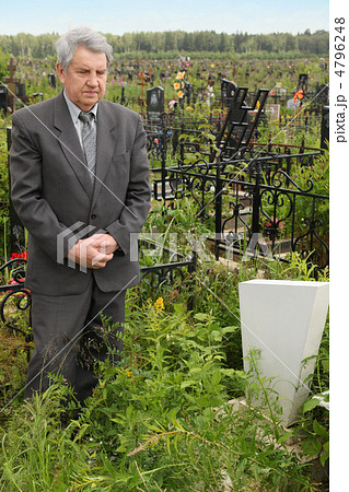 old sad senior in grey suit standing near grave with white grave old sad senior in grey suit standing near grave with white grave 4796248
