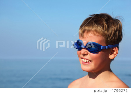 Boy in dark blue glasses for swimming stands near  sea and smile 4796272