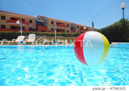 An inflatable ball lies in  pool under open-skies near cottages, 4796305
