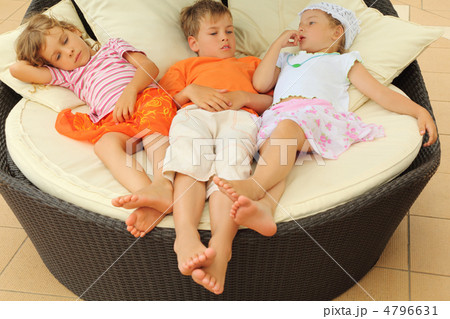 two tired little girls and boy lying on big circle armchair with 4796631