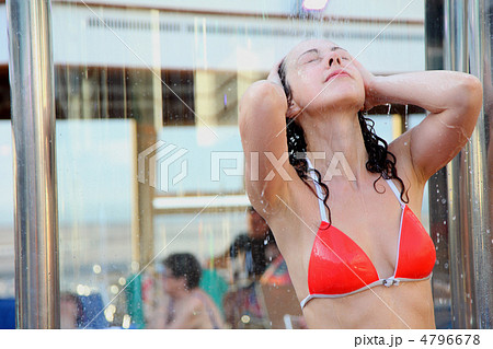 Girl with closed eyes in red swimsuit takes a shower on deck of 4796678