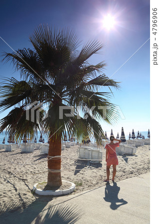 Woman in morning stands on beach after protection near palm Woman in morning stands on beach after protection near palm 4796906