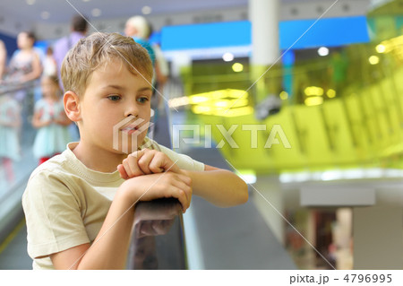 little serious boy standing on escalator and moving up, looking 4796995