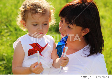 Mother holds the little girl with two colorful pinwheels Mother holds the little girl with two colorful pinwheels 4797023