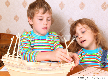 Blonde boy and girl in striped shirt make homemade wooden boat 4797075