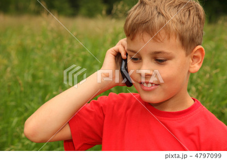 little boy in red shirt talking on cell phone outdoors. Boy smil 4797099
