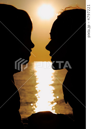 Silhouettes of mother and son in evening at seaside  during suns 4797221