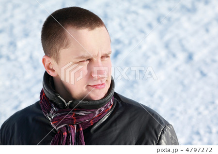 Young man stands on snow in winter and dreamily looks far 4797272