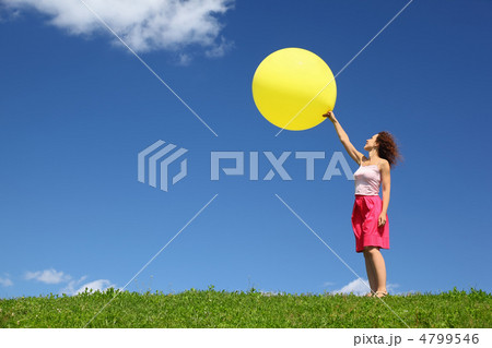 Woman stands in summer on grass and starts  large inflatable bal 4799546
