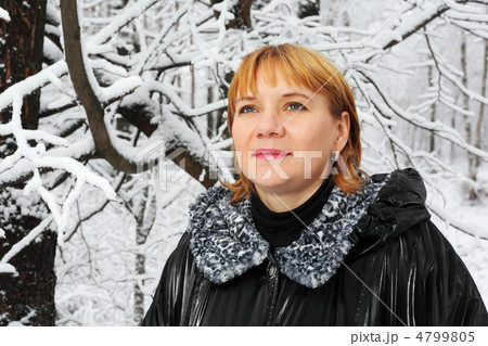 Red-headed woman dressed black jacket look up in woods in snow a Red-headed woman dressed black jacket look up in woods in snow a 4799805