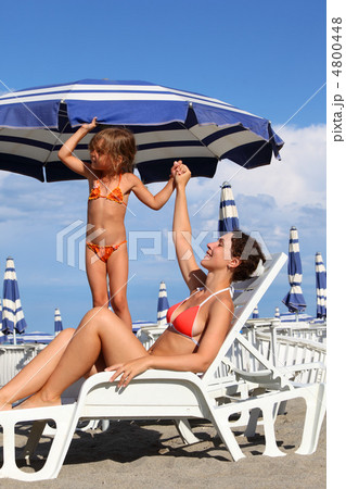 young mother lying on lounger under beach umbrella. little daugh young mother lying on lounger under beach umbrella. little daugh 4800448