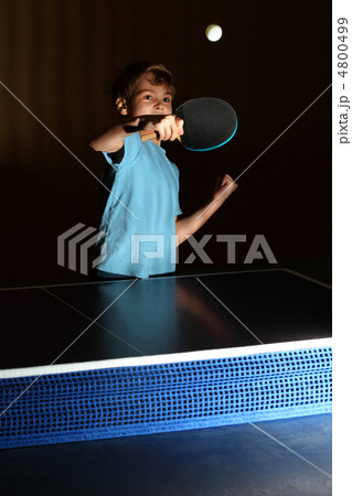 little boy wearing blue shirt playing ping pong; concentrated fa 4800499