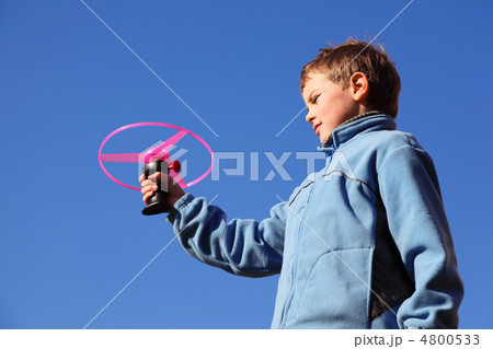 little boy in blue jacket plays with pink propeller. in backgrou 4800533