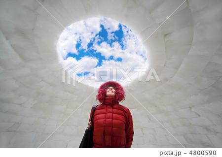 beautiful young woman in red jacket standing inside igloo at win 4800590
