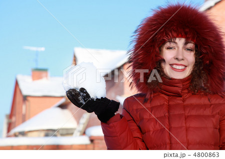 beautiful young woman in red jacket keeps snow and smiles at win 4800863