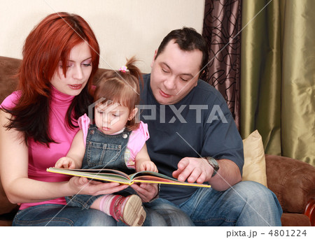 mother, father and little daughter in denim jumpsuit reads book 4801224