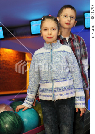 Brother and sister stand alongside near balls for bowling, focus 4801293