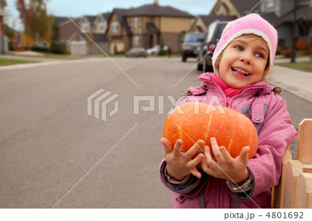 Smiling girl goes on road and bears pumpkin in hands Smiling girl goes on road and bears pumpkin in hands 4801692