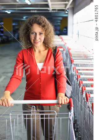 beautiful young woman with cart standing in indoor car park, row 4801765