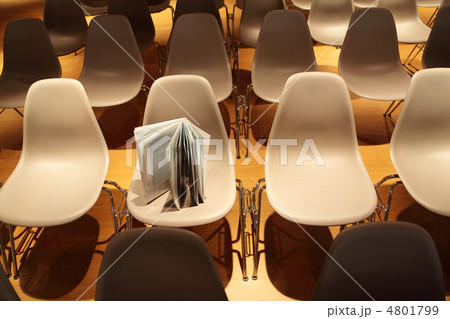 several rows of white plastic chairs; brochure standing on chair 4801799