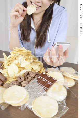 スナック菓子を食べながらスマホを見る女性 4822449