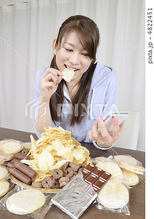 スナック菓子を食べながらスマホを見る女性 4822451