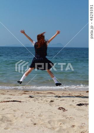 海でジャンプする女子高生の写真素材