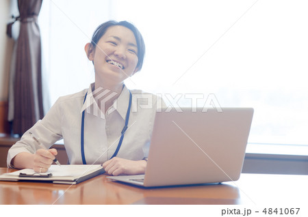 逆光の窓辺でノートパソコンを前に書き仕事をする女性 4841067