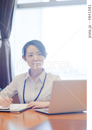 逆光の窓辺でノートパソコンを広げ書き仕事をしている女性 4841081