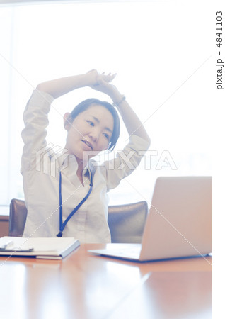 逆光の窓辺で伸びをしながらノートパソコンを見る女性 4841103