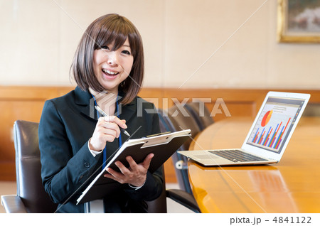 ノートパソコンの前で資料とペンを持ち笑って話しかける女性 4841122