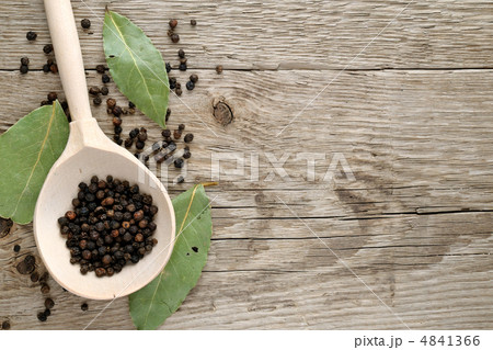 Black pepper in spoon and dry bay leaf on wooden background 4841366