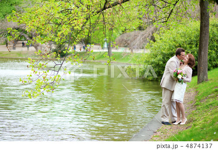 Happy just married couple hugging and kissing near the lake in p 4874137