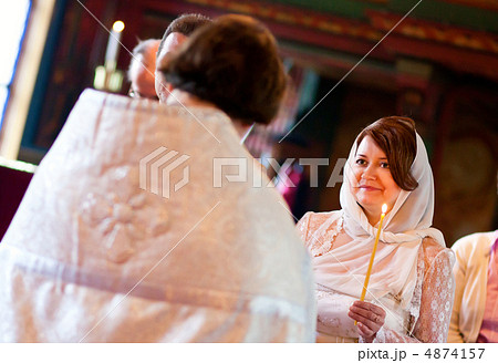 Happy bride is listening to priest during orthodox wedding cerem Happy bride is listening to priest during orthodox wedding cerem 4874157