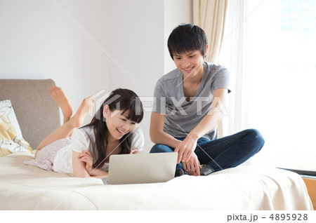 ベッドの上でPCを見るカップル 4895928