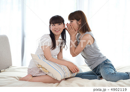 ベッドルームで内緒話をする女性の写真素材